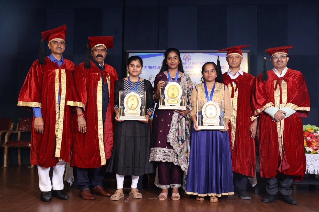 Students holding awards with representatives of the management and principal at a felicitation programme